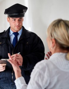 Policeman at door talking to woman who is hiding fugitive