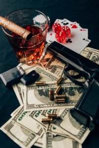 Gun on top of playing cards, dice, and cash