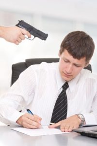 Man signing a paper under duress because a gun is being held to his head