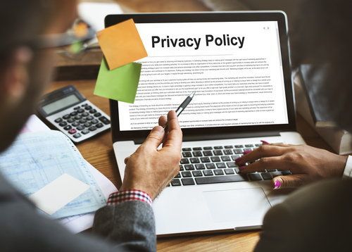 Dos personas trabajando en una computadora donde la pantalla dice "política de privacidad"