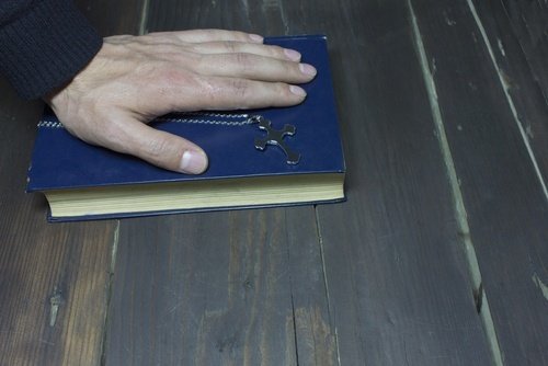 hombre poniendo la mano sobre la Biblia - dar un testimonio falso bajo juramento puede ser procesado como perjurio en Colorado