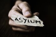 hand holding out piece of paper with word "asylum" written on it