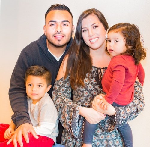 padres hispanos sonrientes con sus dos hijos