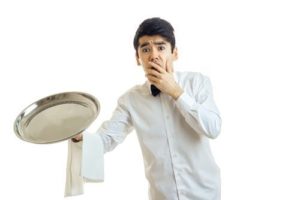 Waiter in white uniform holding up tray