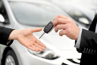 Primer plano de una persona entregando la llave del coche a otra persona