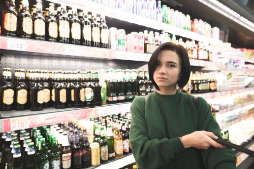 adolescente en supermercado en el pasillo de alcohol - solicitar la venta de alcohol puede ser un delito en California