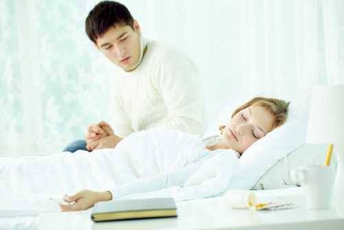 Young man looking at his wife lying in hospital bed