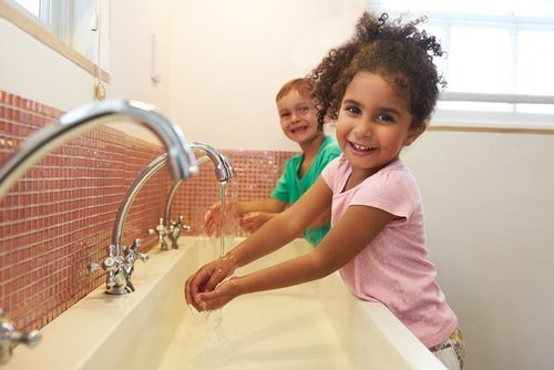 Young boy and young girl washing their hands in school bathroom