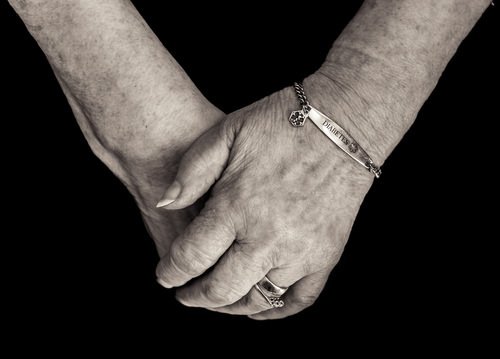 Manos de una anciana usando una pulsera para diabéticos - los diabéticos con cetoacidosis pueden registrar lecturas falsamente altas en el alcoholemetro de DUI