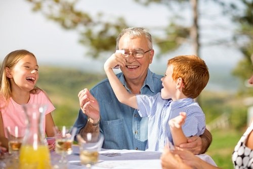 abuelo jugando al aire libre con sus dos nietos pequeños