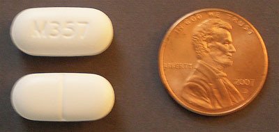 two hydrocodone pills next to a penny