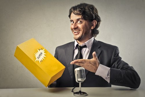 hombre vestido con traje en el micrófono señalando un producto en una caja amarilla como ejemplo de lo que podría ser publicidad engañosa en violación del Código de Negocios y Profesiones 17500