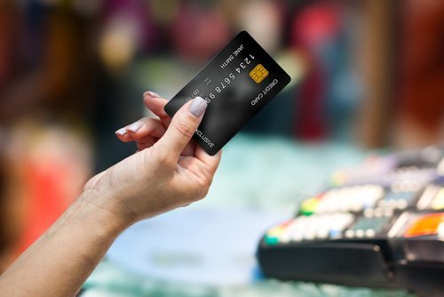 Hand holding a credit card - credit card fraud is a criminal offense in Colorado