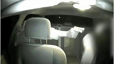 Man pointing a gun inside a car as an example of discharging a firearm from a vehicle, prohibited by NRS 202.287