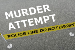 Vista del suelo con las palabras "Intento de asesinato" y una cinta amarilla que dice "Línea de la policía, no cruzar"