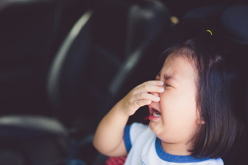 niño inmigrante llorando en el asiento trasero de un coche conducido por un conductor borracho
