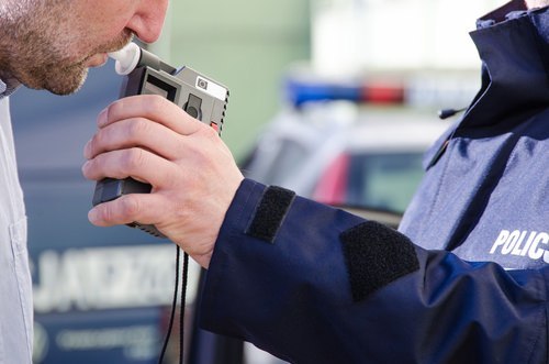middle aged man blowing on breathalyzer at a DUI traffic stop