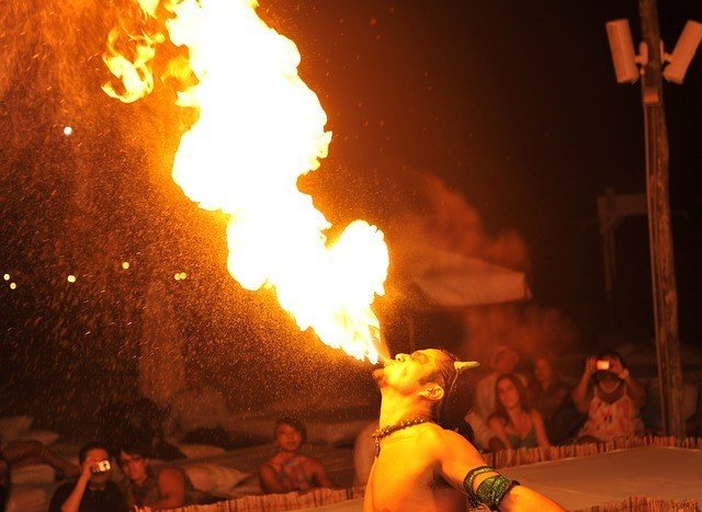 hombre respirando fuego frente a una multitud por la noche