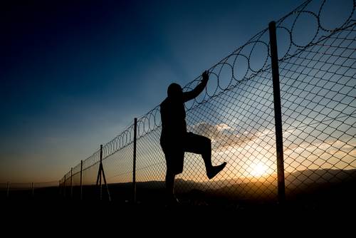 inmate climbing a chain-linked prison fence - escaping from jail or prison is a crime in Nevada under NRS 212.090