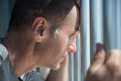 un recluso mirando desde una celda de la cárcel - una violación del Código Penal 20410 PC puede llevar hasta 3 años de prisión
