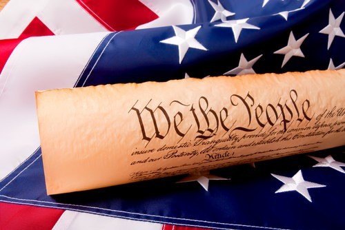 US Constitution rolled up on top of American Flag