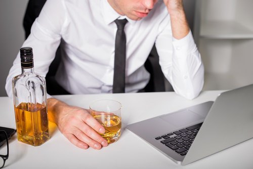 hombre en la computadora bebiendo (presentando una demanda por lesiones laborales en Nevada)