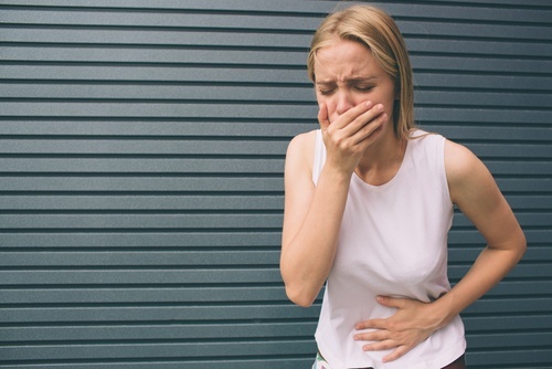 una mujer sosteniendo su boca a punto de vomitar