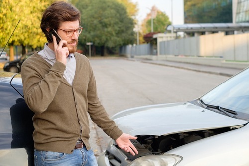 joven en teléfono celular después de un accidente automovilístico llamando a su aseguradora