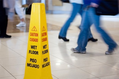 Wet floor sign on floor with pedestrians walking