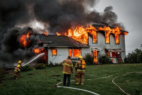 incendio de casa con bombero extinguiéndolo