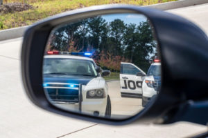 Side view mirror showing patrol cars in the background.