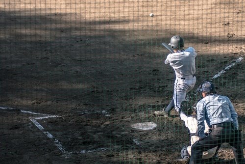 catcher and batter who has just hit ball. Photo from behind home plate net.