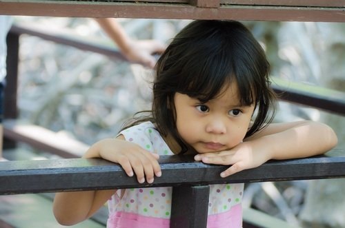 lonely little Asian girl looking over railing alone