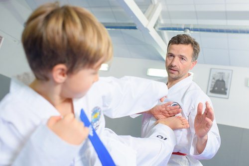 Adult male practicing martial art with young boy, which is a legal activity