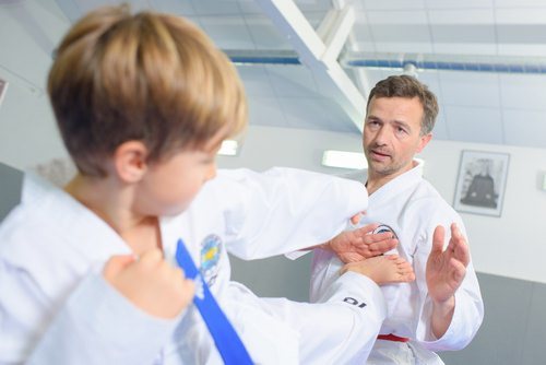 Adult male practicing martial art with young boy, which is a legal activity