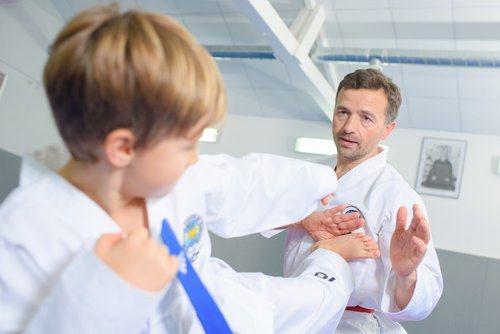 Hombre adulto practicando artes marciales con un niño, lo cual es una actividad legal