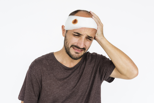 hombre sosteniendo su cabeza envuelta en un vendaje ensangrentado