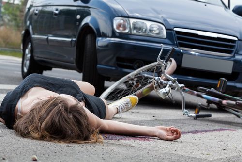 mujer en el suelo después de un choque entre un automóvil y una bicicleta