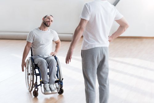 man in wheelchair doing physical therapy with trainer