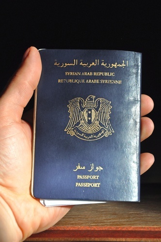 man's hand holding Syrian passport