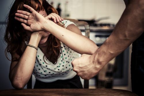 hombre adulto sosteniendo el puño junto a una mujer adulta víctima de violencia doméstica