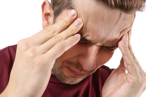 joven hombre gimiendo de dolor y sosteniendo las manos en la cabeza