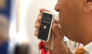 man blowing into a breathalyzer