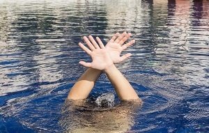Person drowning and waiving hands just above the water surface