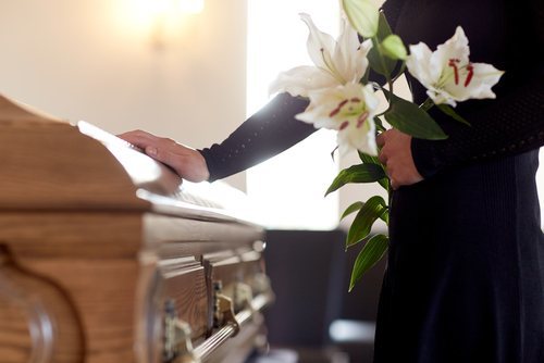 woman holding lilies with her hand on a casket