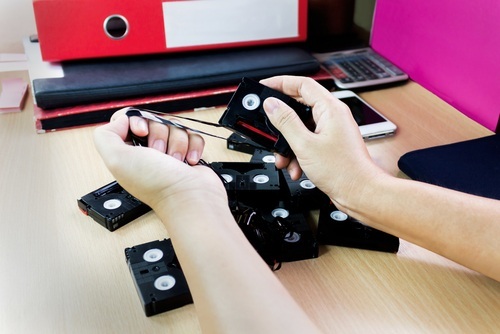 hands of someone destroying pulling tape out of mini-cassettes