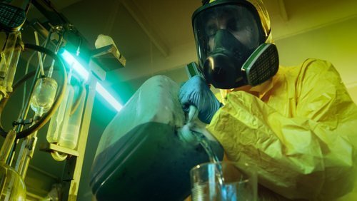 man in hazmat suit pouring chemicals in a container