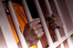 Man's hands holding jail bars