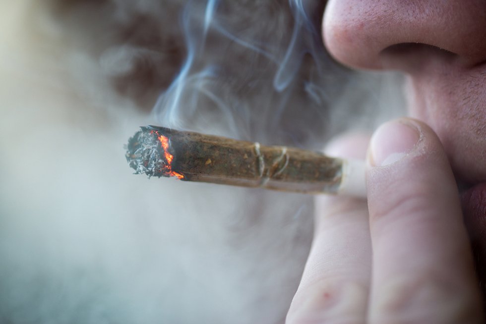 Un hombre fumando un porro de marihuana.