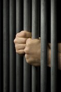 manos de recluso agarrando barras de la cárcel